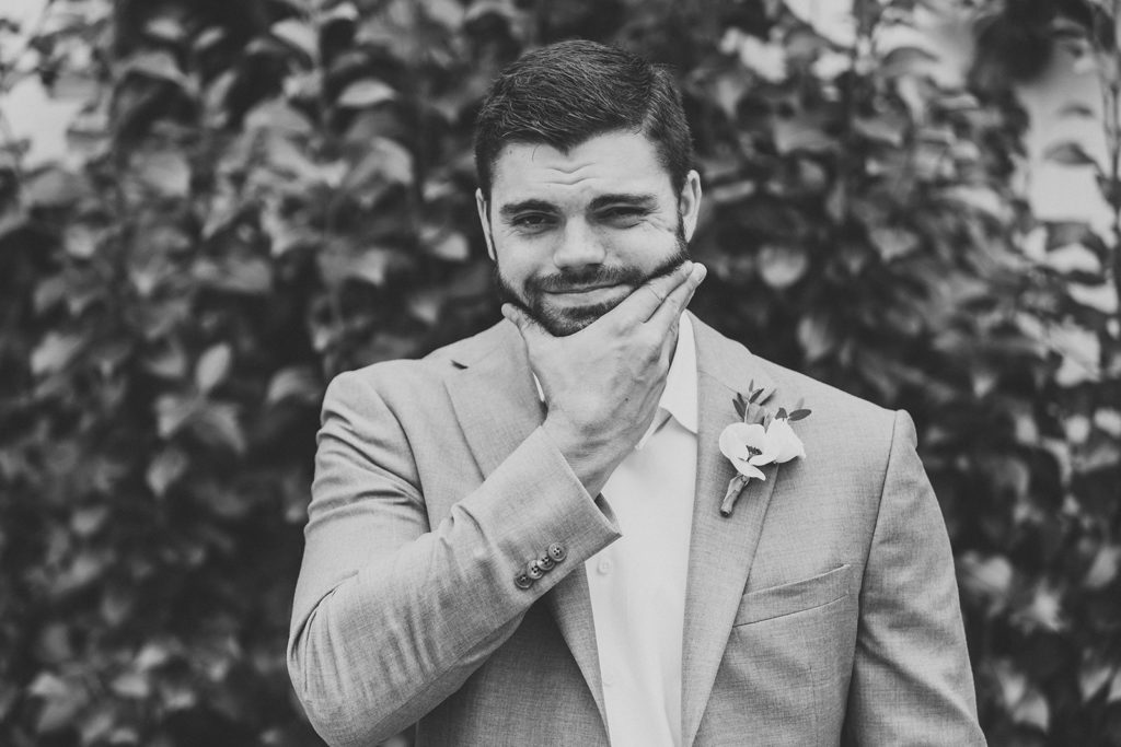 black and white photo of groom stroking beard in Ritz Charles garden before his Carmel backyard wedding