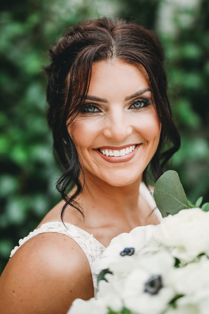 close up of smiling bride with gorgeous green eyes and brown hair before her Carmel backyard wedding
