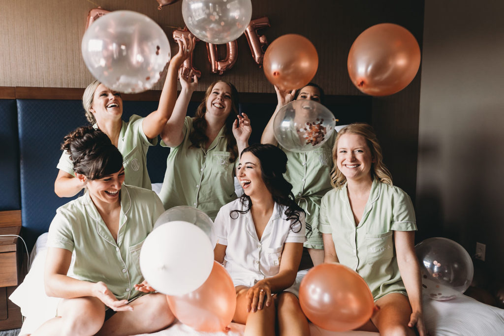 bride and bridesmaids with balloons on bed at embassy suites in south bend
