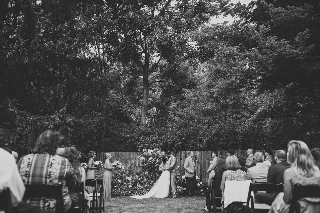 black and white photo of bride and groom sharing first kiss at their Carmel backyard wedding