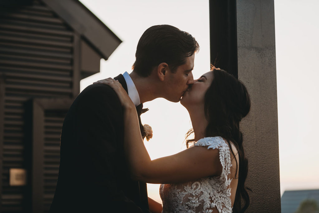 bride and groom kiss on rooftop of embassy suites in south bend during their notre dame wedding