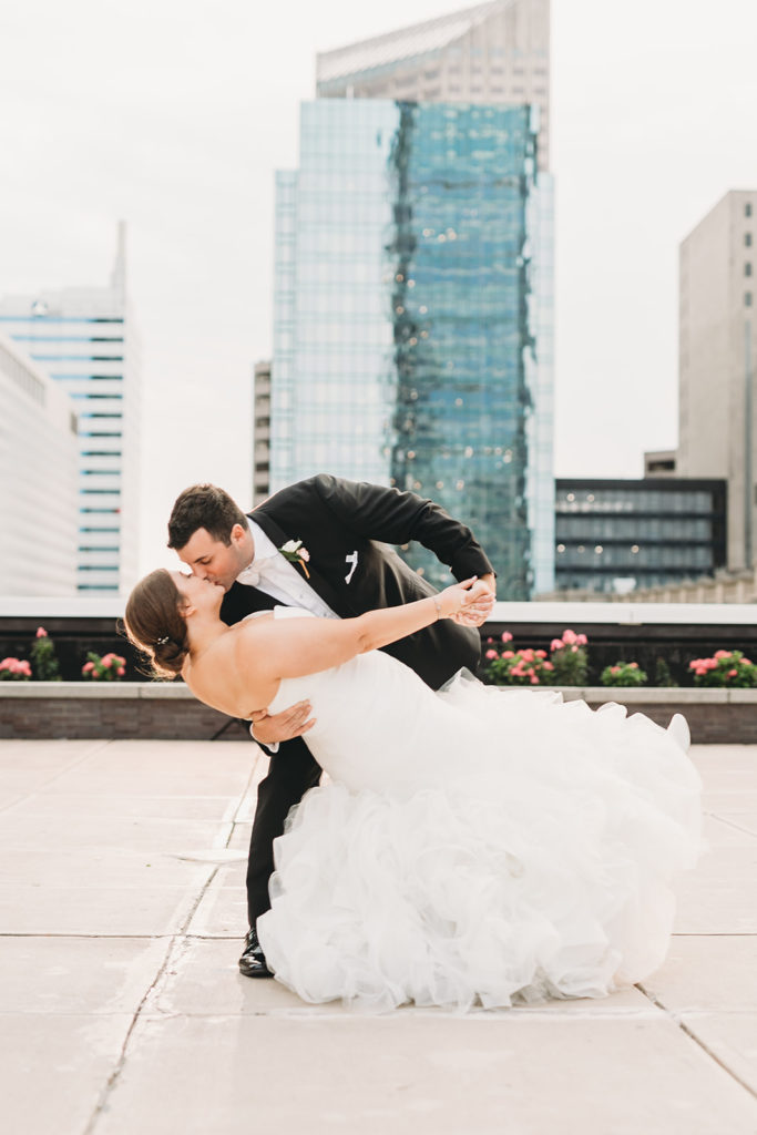 groom dips bride and kisses her at sunset during their Charming Regions Tower Wedding