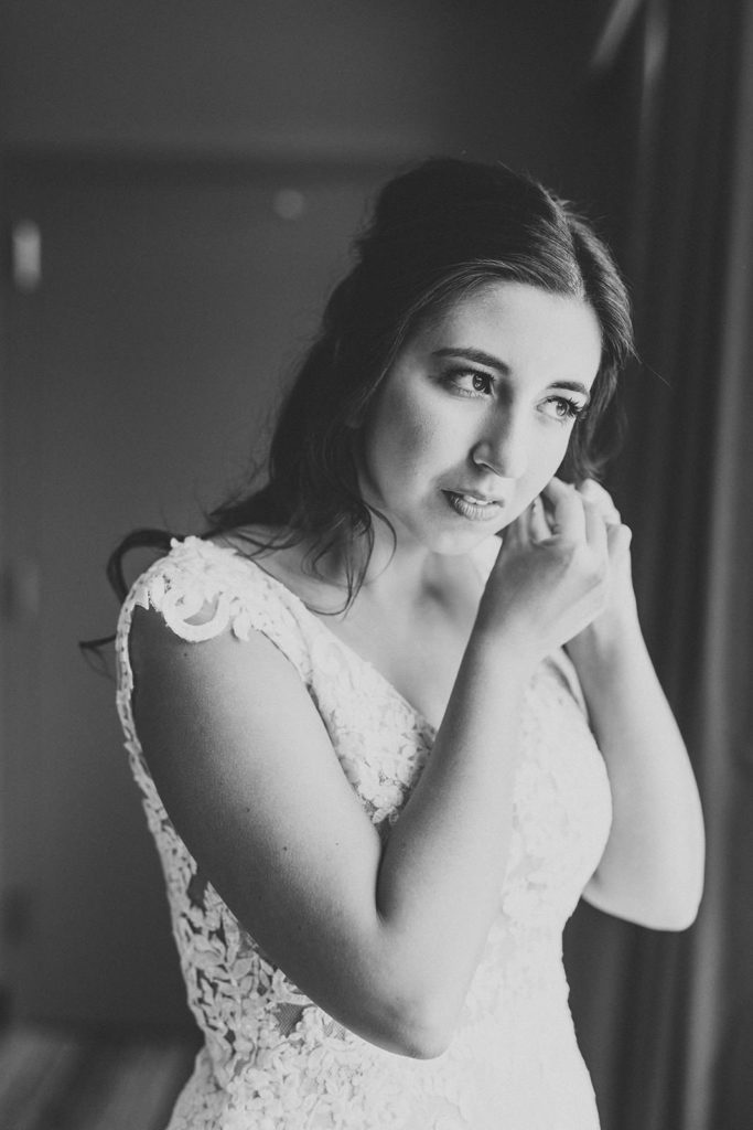 black and white photo of bride putting earrings in her ears at embassy suites in south bend