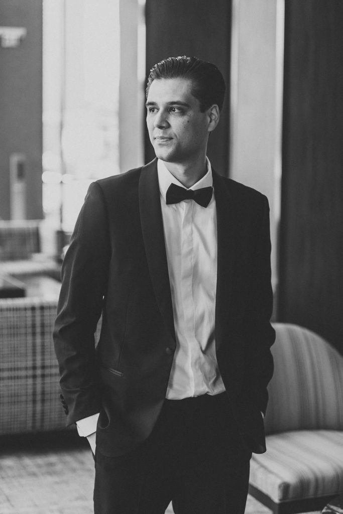 blick and white photo of groom in tux in embassy suites in south bend lobby
