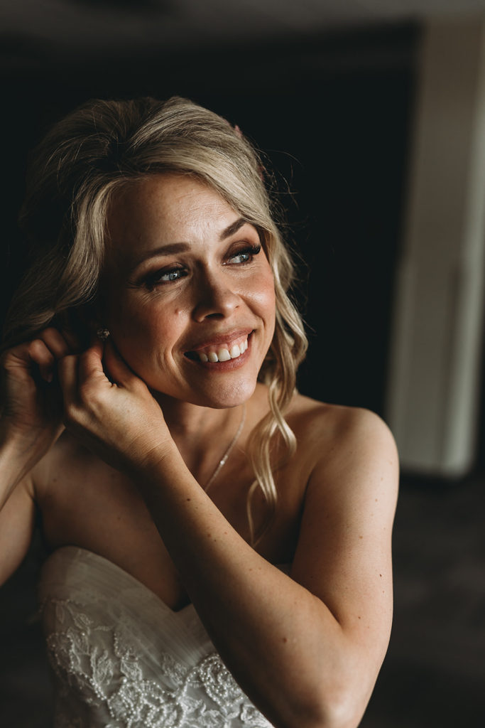 Bride puts in one of her earrings in her unique wedding photos