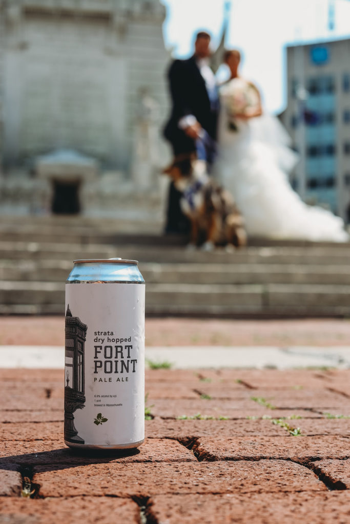 strata dry hopped fort point pale ale can on cobbblestones in focus in front of bride and groom with their dog during their Charming Regions Tower Wedding