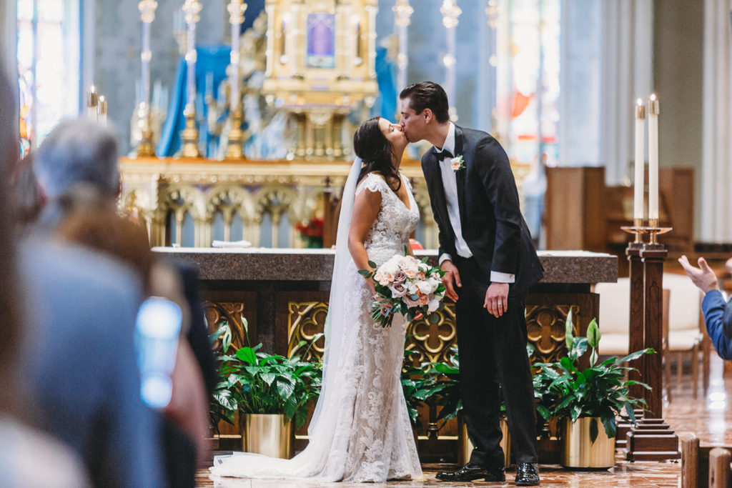 bride and groom first kiss mid shot during their Notre Dame Wedding at the Basilica of the Sacred Heart