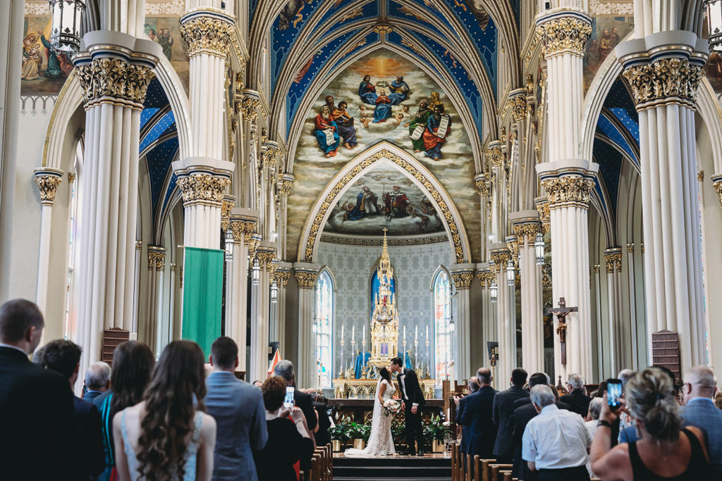 wide shot of bride and groom first kiss during their Notre Dame wedding at the Basilica of the Sacred Heart