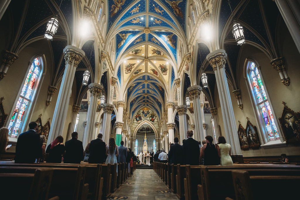 wide shot of bride and groom and guests at Basilica of the Sacred Heart for their University of Notre Dame wedding