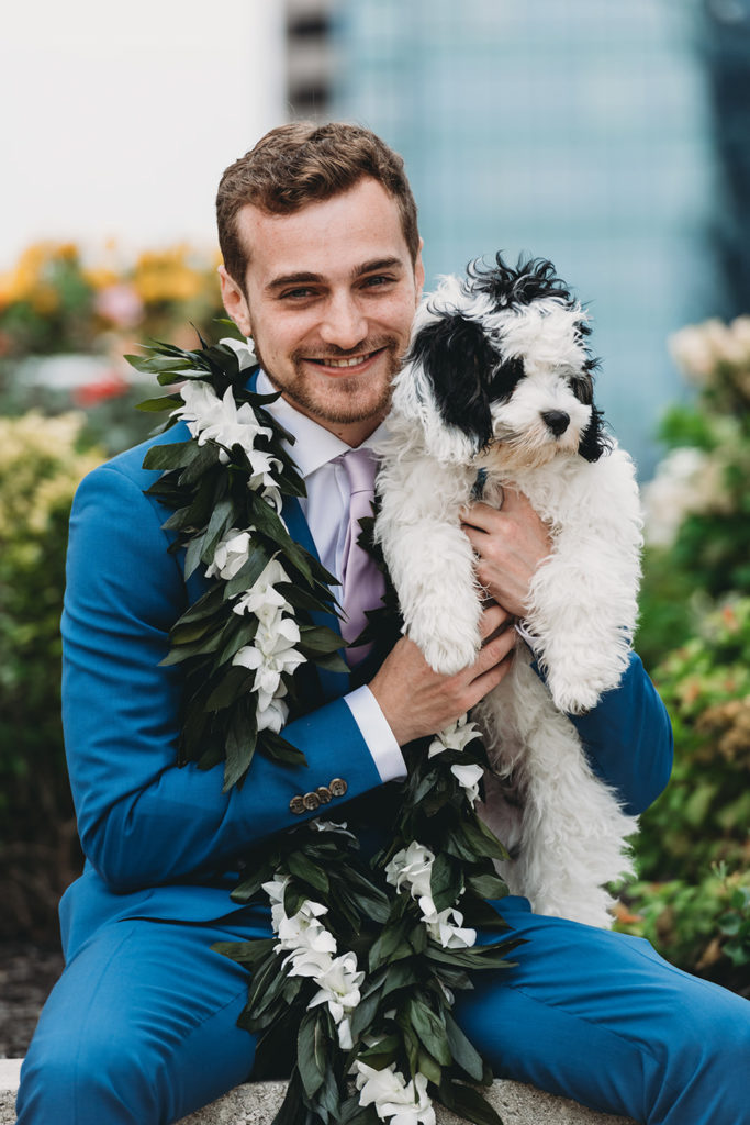 groom in lei holding his dog at their Indianapolis Hawaiian Jewish Wedding