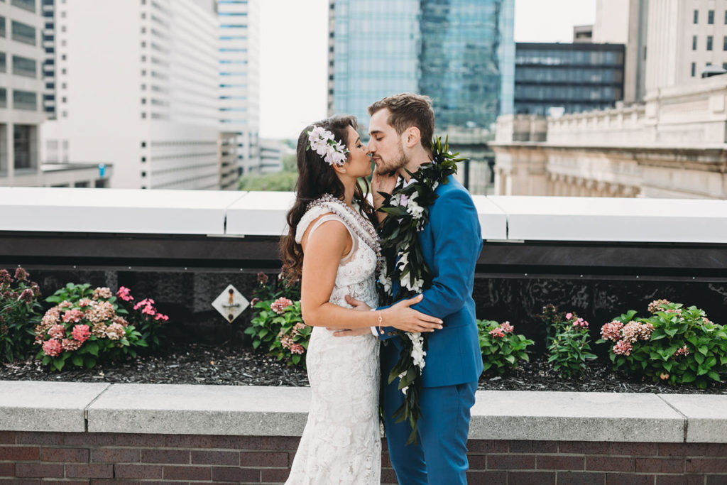 bride and groom kiss on regions tower rooftop terrace at their Indianapolis Hawaiian Jewish Wedding