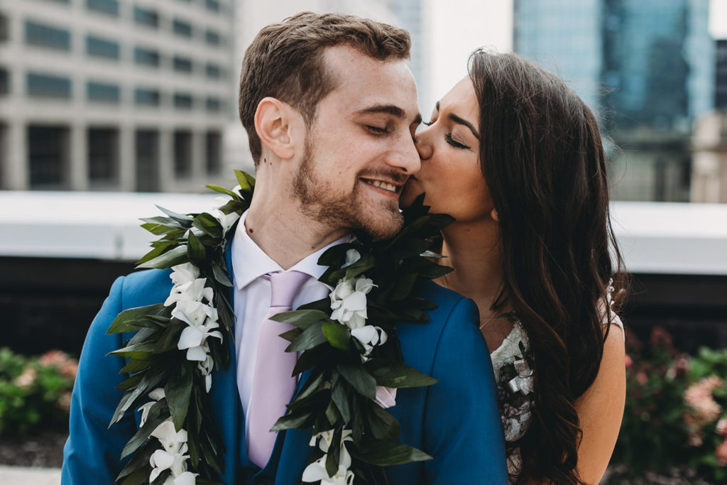 bride hugs groom from behind and kisses him on cheek at their Indianapolis Hawaiian Jewish Wedding