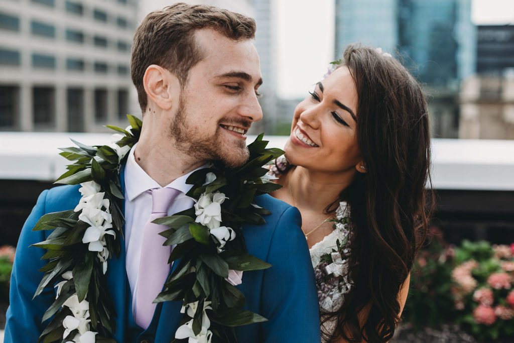 bride smiles at groom while hugging him from behind at their Indianapolis Hawaiian Jewish Wedding