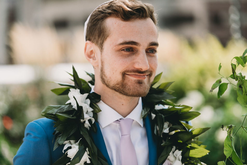 groom smiles when he sees bride walking down the aisle at their Indianapolis Hawaiian Jewish Wedding