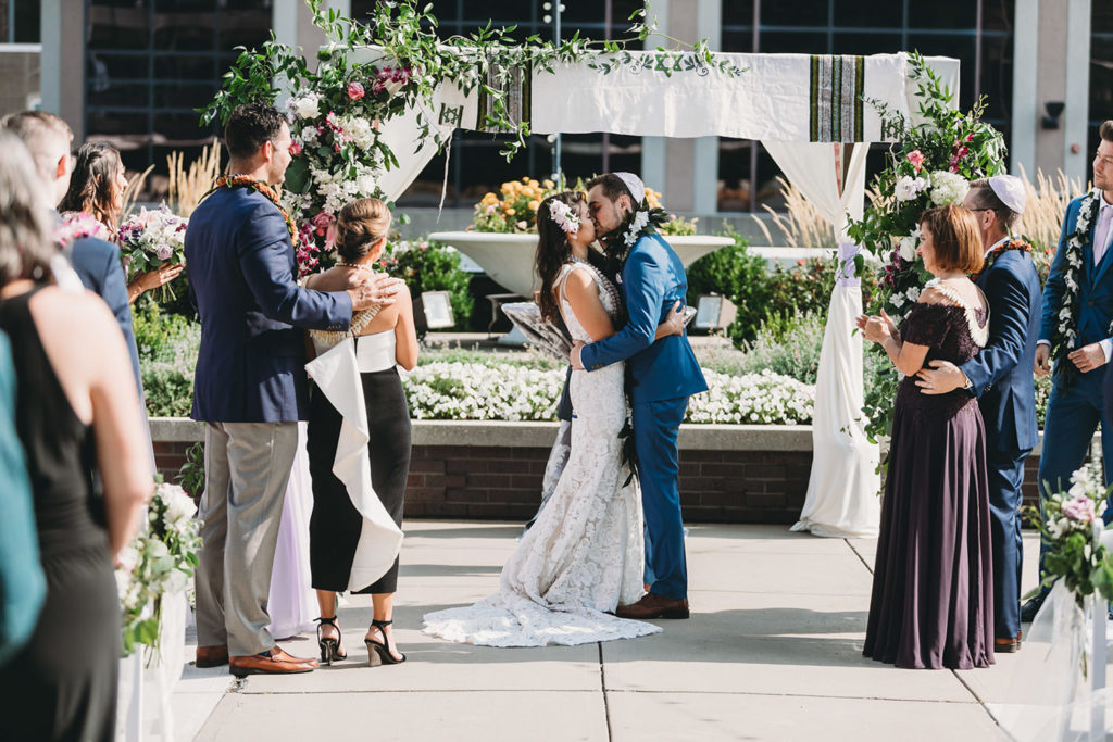 bride and groom kiss under the chuppah at their Indianapolis Hawaiian Jewish Wedding