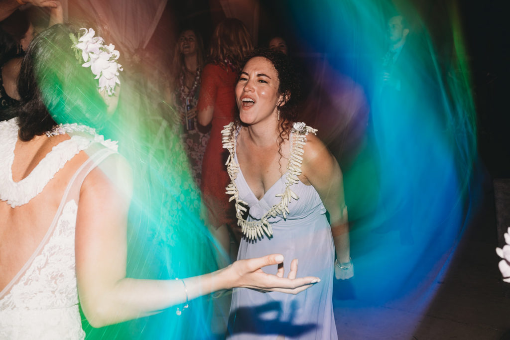 bride dances with sister in rainbow lights at their Indianapolis Hawaiian Jewish Wedding