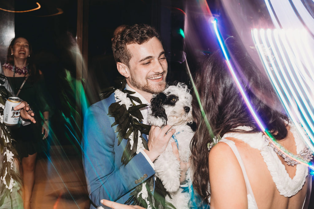 groom holds dog during reception at their Indianapolis Hawaiian Jewish Wedding