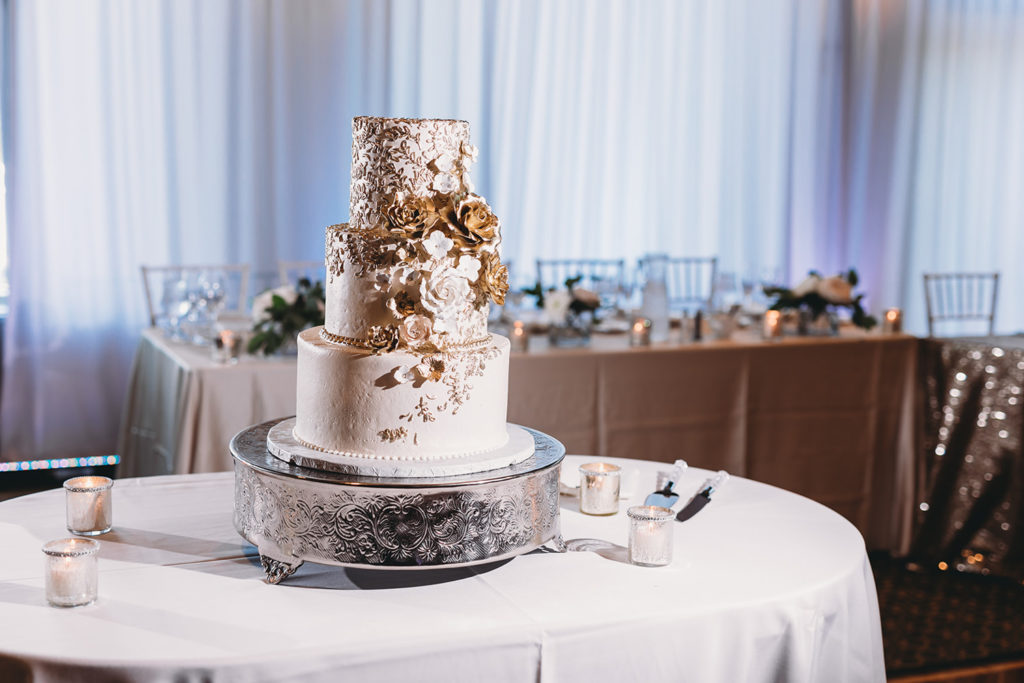 wedding cake with gold and white flowers at a sand creek wedding