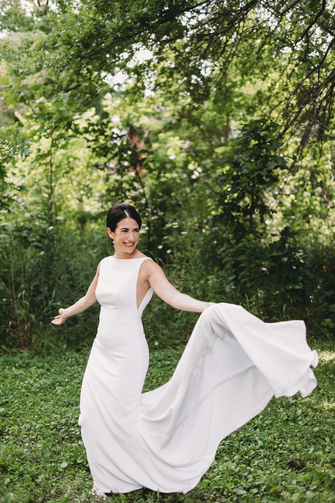 bride dancing while holding the train of her dress as it flutters around her before her charming coxhall gardens wedding