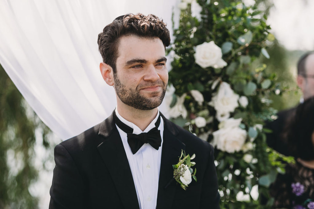 groom smile when he sees bride coming down the aisle