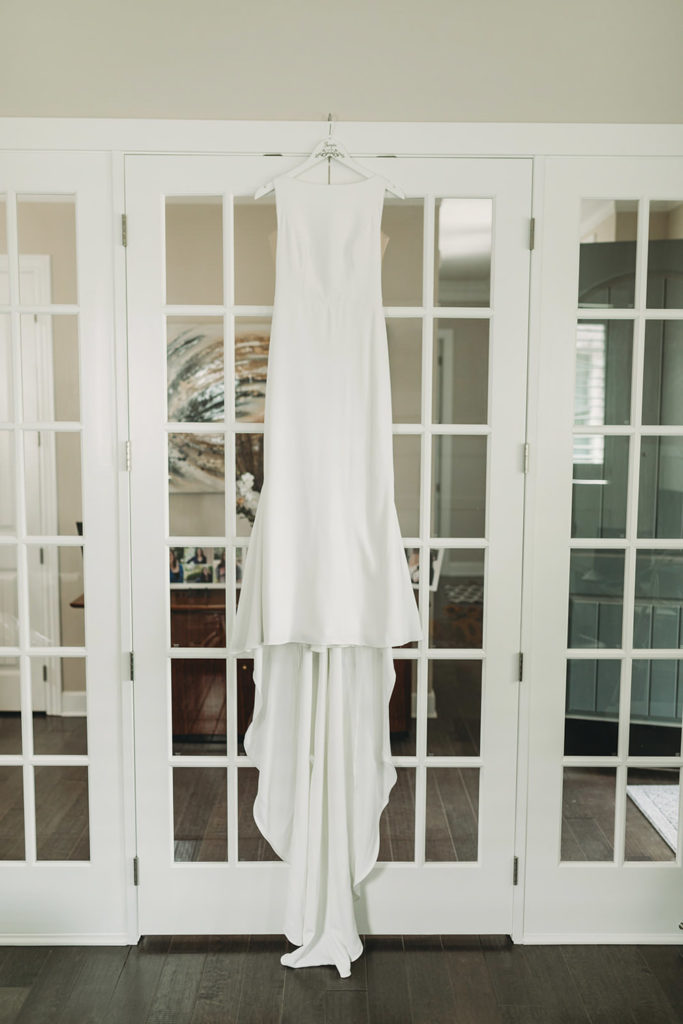 white wedding dress hanging on glass doors