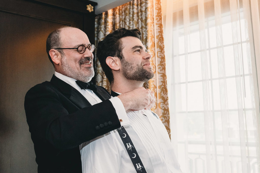 groom's dad ties groom's bowtie onto him