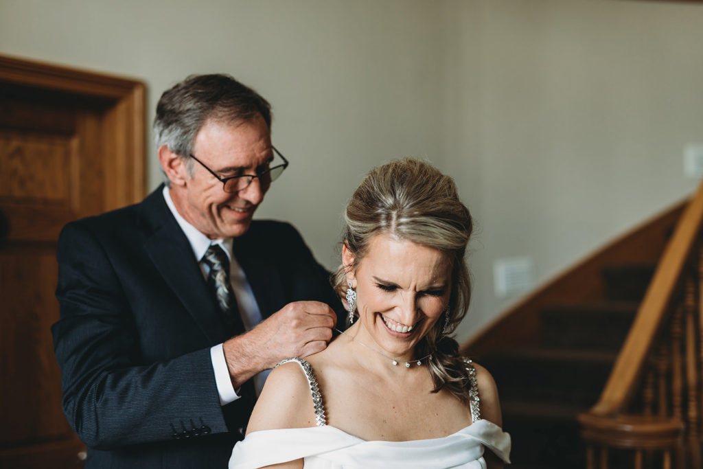 groom puts a necklace on a bride during their five willows wedding