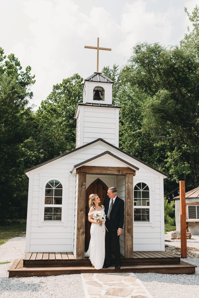 bride and groom in front of a small chapel during their five willows wedding
