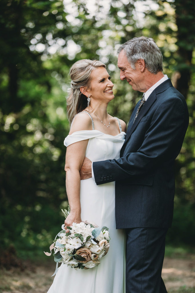 groom hugs bride and smiles in the forest during their five willows wedding