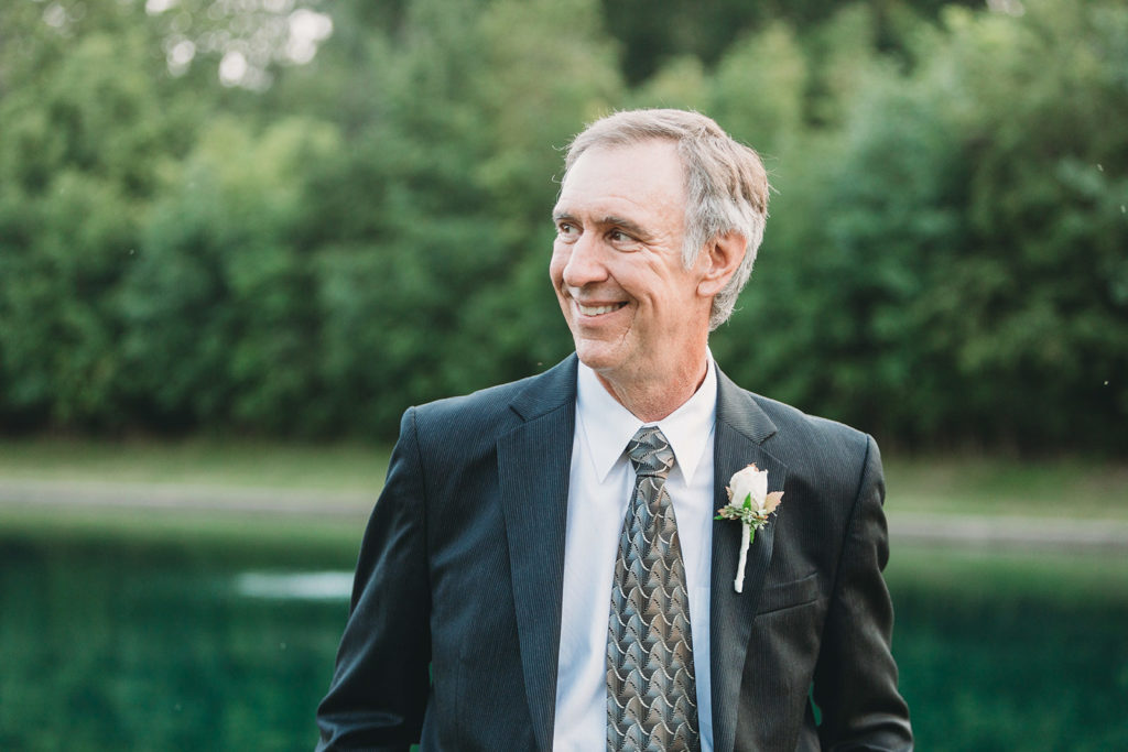 groom smiling in front of a pond