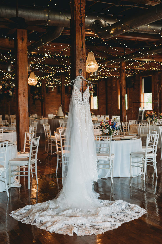 wedding dress hanging with fairy lights behind it during a charming mavris wedding