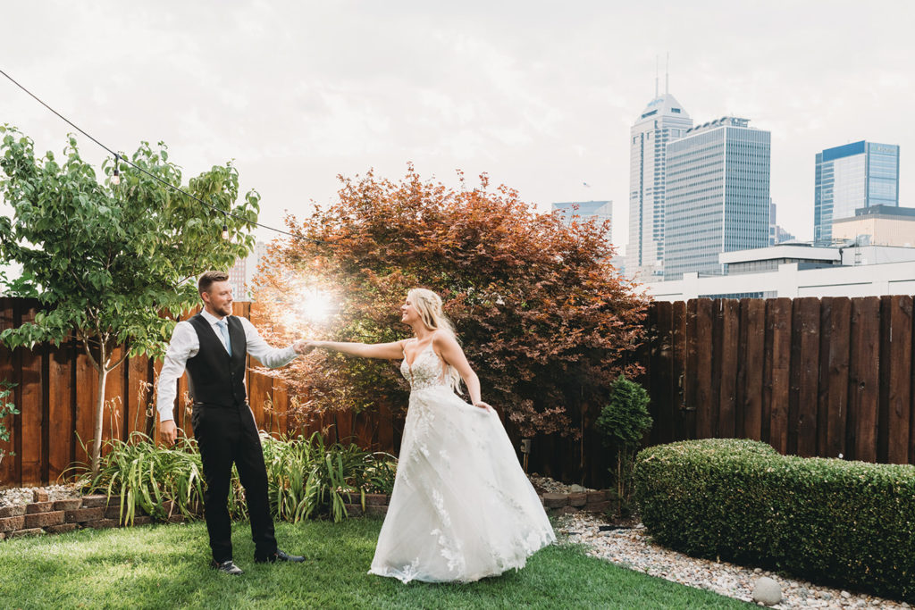 bride and groom dance at sunset outside with indy skyline behind them during their charming mavris wedding