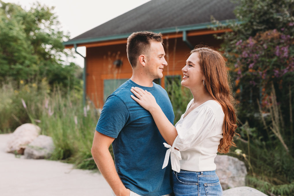 man and woman hug in front of orange building during their eagle creek park engagement session