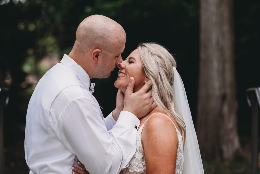 groom holds bride's face as he kisses her during a marian university wedding