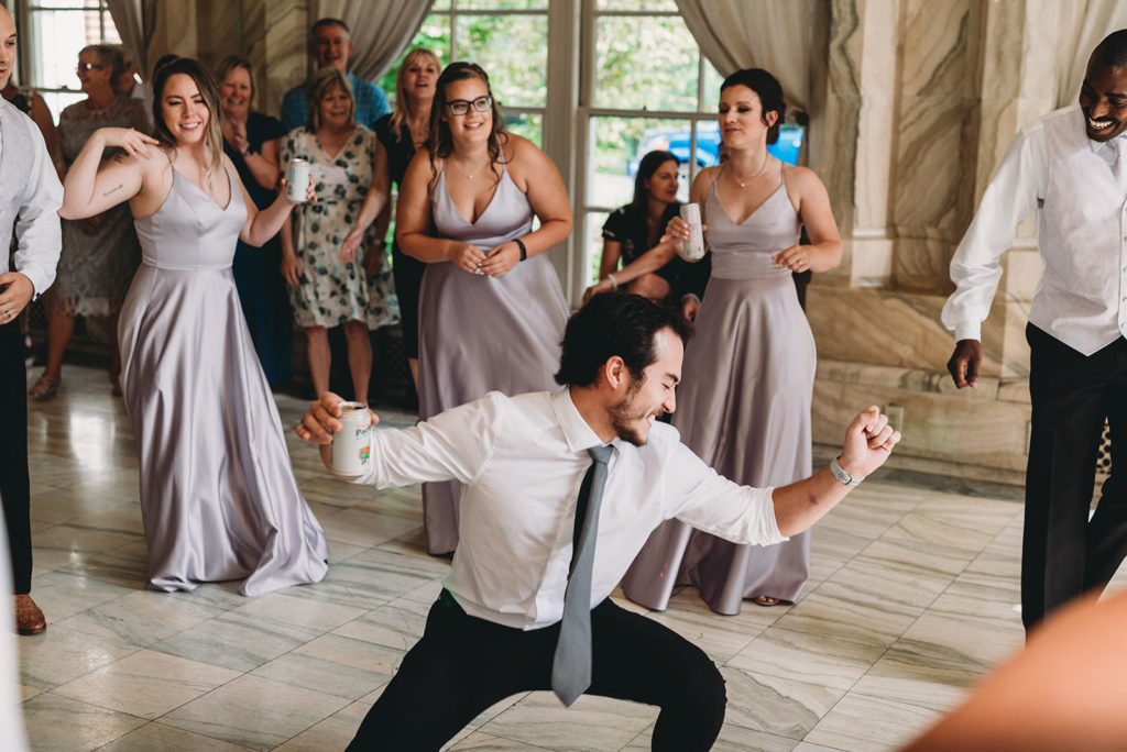 a man gets low on the dance floor while other wedding guests watch during a marian university wedding