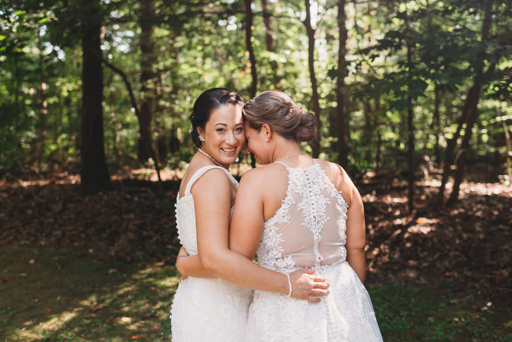 two brides side hug and one rests her forehead on the other's cheek during their Martinsville wedding