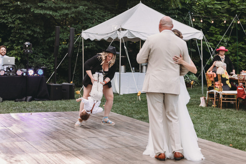 a woman grabs a young boy and carries him off the dance floor during the first dance at a Minnetrista wedding