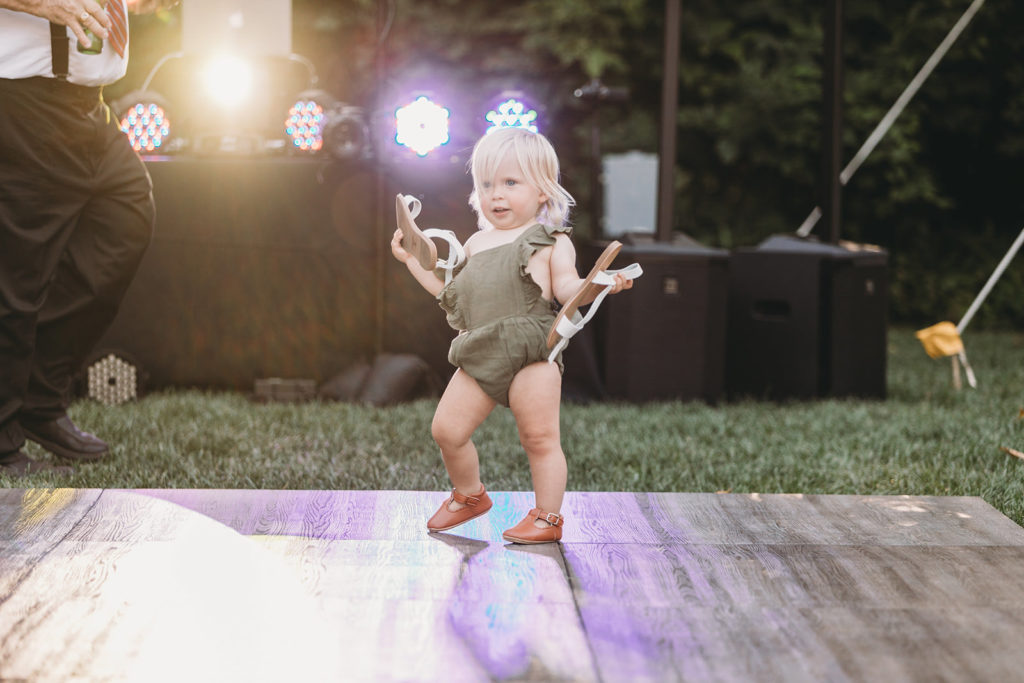 small blonde baby in green onesie dancing during a Minnetrista wedding