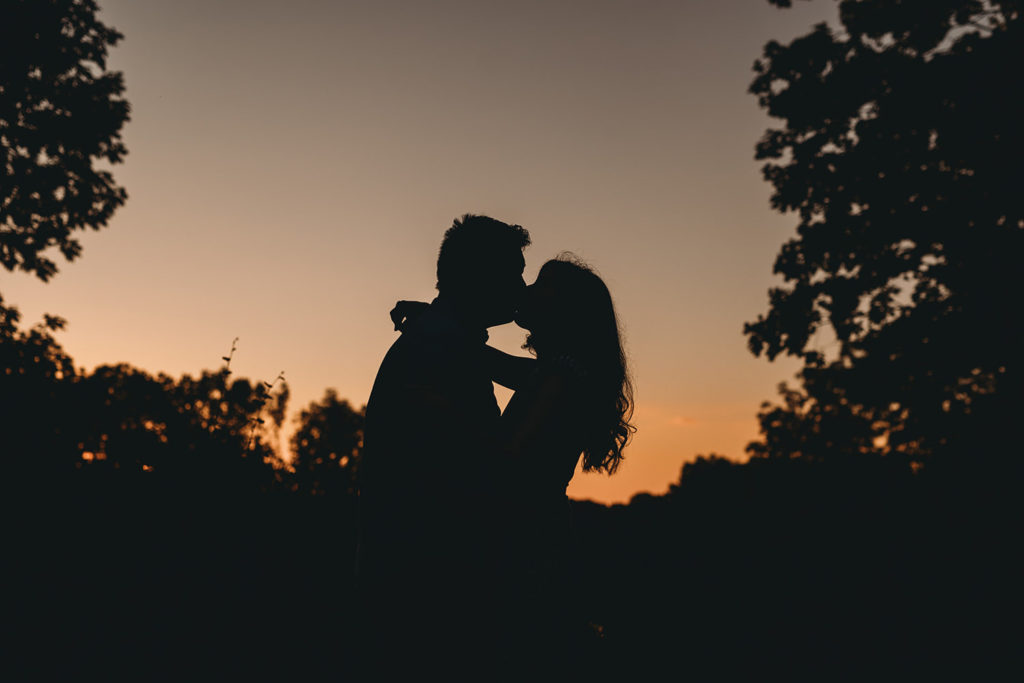 silhouette of a man and a woman kissing at sunset during their newfields greenhouse engagement photos