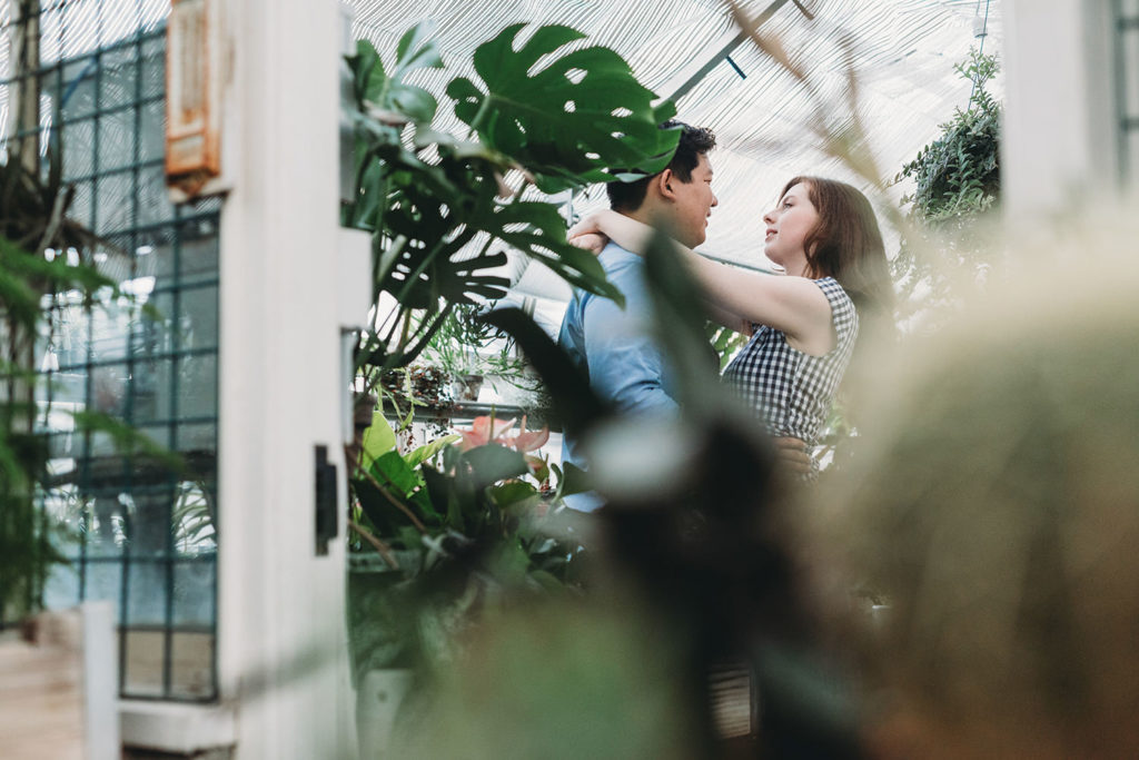a man and a woman dance inside a glass building during their newfields greenhouse engagement photos