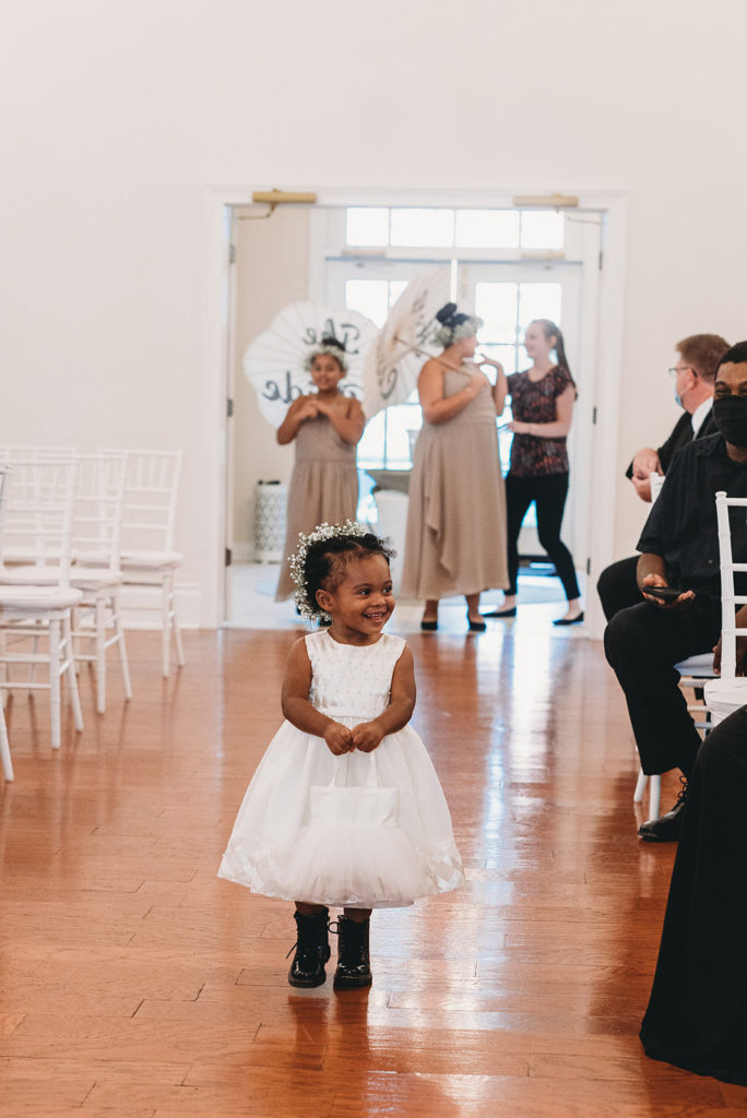 a flower girl toddler walking down the aisle during their Ritz Charles wedding