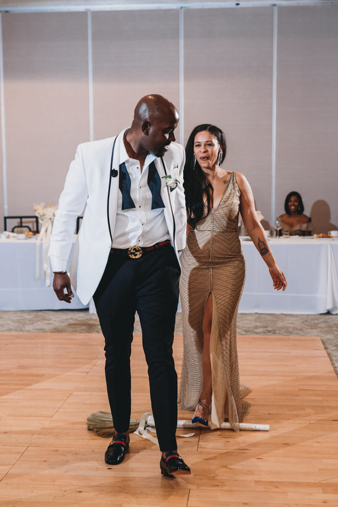 bride and groom step over a broom during their Ritz Charles wedding