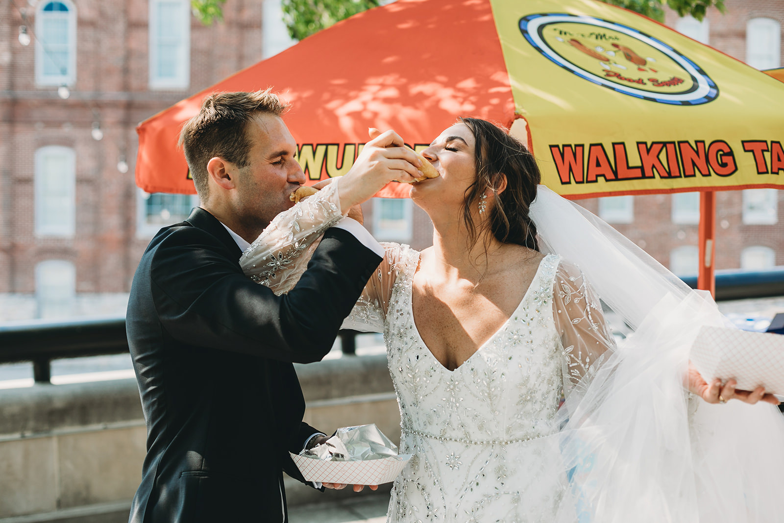 a bride and groom eat hot dogs from a hot dog cart before their scottish rite cathedral wedding