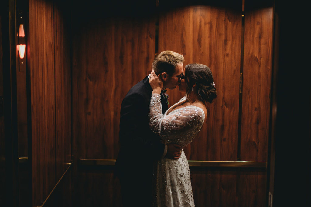 bride and groom kissing in an elevator as the door closes during a scottish rite cathedral wedding