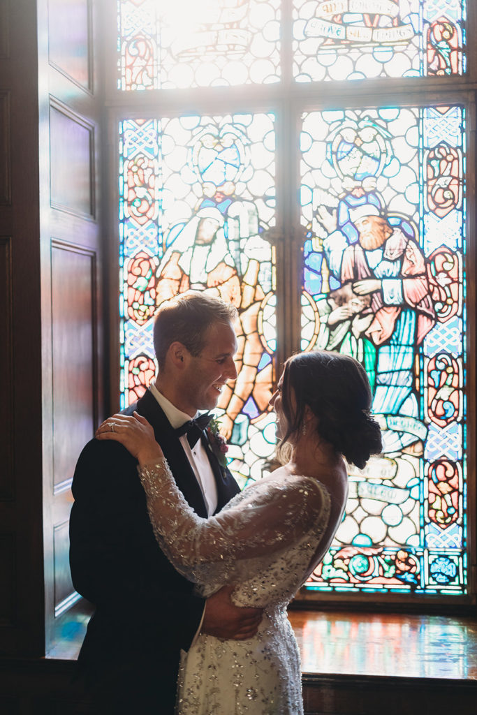 bride and groom hug in front of stained glass during a scottish rite cathedral wedding