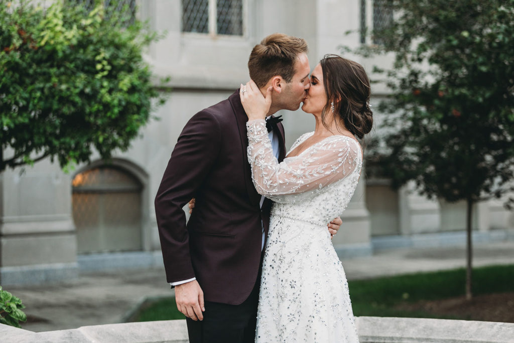 bride and groom kiss while hugging on the street outside the scottish rite cathedral during a scottish rite cathedral wedding