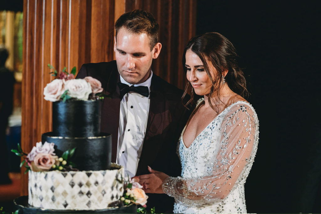 bride and groom cut black wedding cake during a scottish rite cathedral wedding