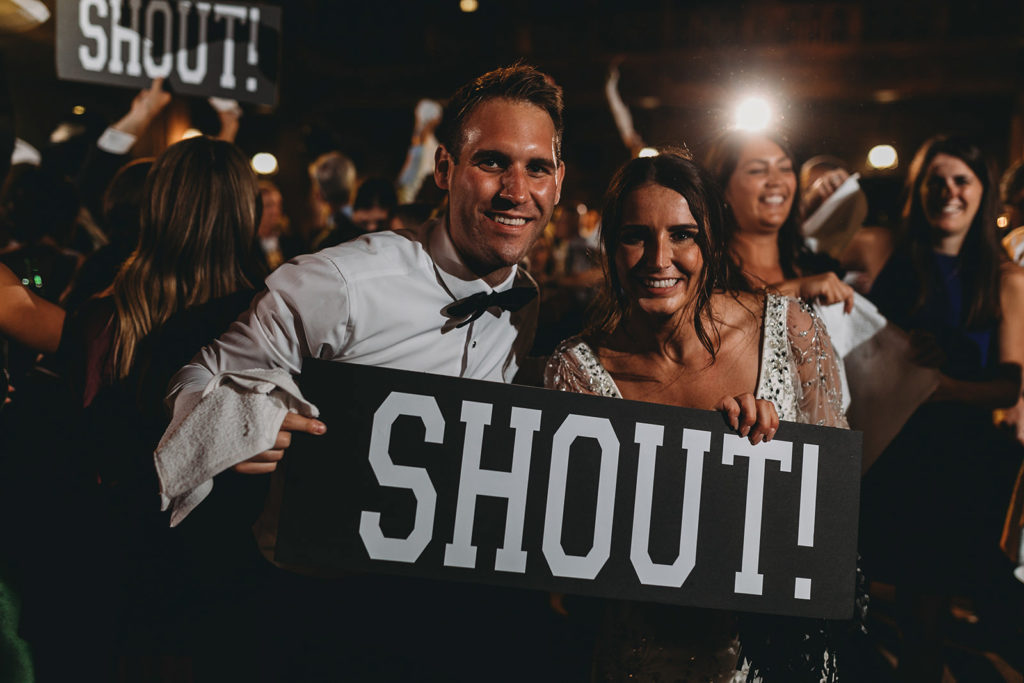 bride and groom holding a sign that says shout during a scottish rite cathedral wedding