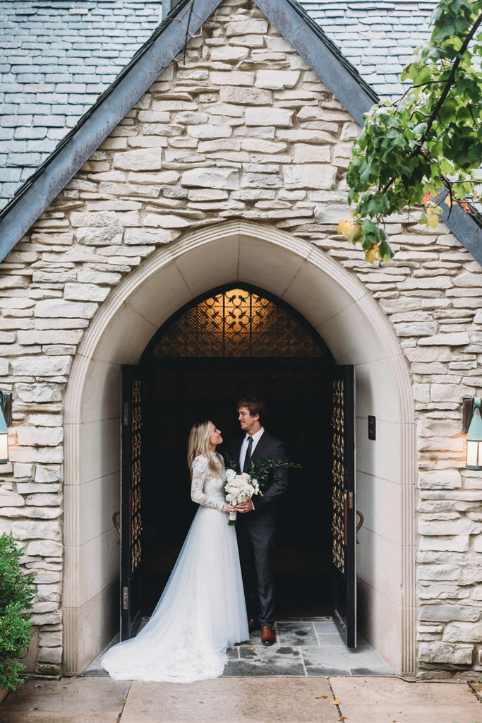 bride and groom stand in the entry to beck chapel on rainy day during their indiana university wedding