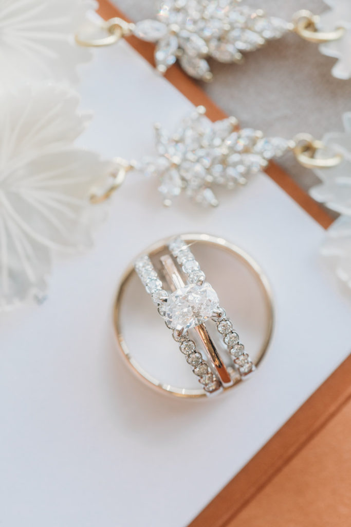 rings on a white backdrop with earrings during a mustard seed wedding